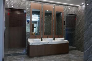 A modern bathroom with a marble floor, a large vanity with two sinks, and a mirror with three panels. - Yongping Hotel (Xiong County)