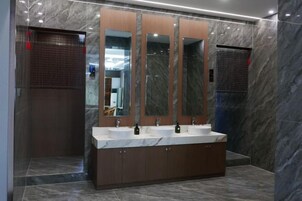 A modern bathroom with a marble floor, a large vanity with two sinks, and a mirror with three panels.
