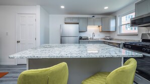 Una cocina moderna con encimera de granito, electrodomésticos de acero inoxidable y una ventana que deja entrar luz natural.