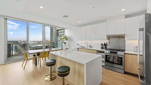 A modern kitchen with a large island, stainless steel appliances, and a city view through floor-to-ceiling windows. - @marbella Lane - 3BR Coastal Retreat w/ Luxe Touch (Long Beach)