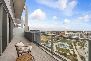 Een balkon met uitzicht op een stadsgezicht, een zwembadgedeelte en een stoel.