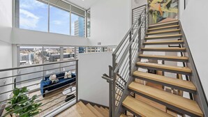 A modern interior with a staircase, large windows, and a city view. - @marbella Lane - 3BR Coastal Retreat w/ Luxe Touch (Long Beach)