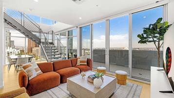 Ein geräumiges Wohnzimmer mit großem Fenster, einer Treppe und Blick auf die Stadt.