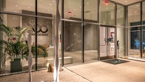 Une entrée moderne avec des portes en verre, une enseigne indiquant « Ocean » et un paillasson orné d’un logo.