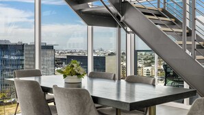 Un espace de bureau moderne doté d’une grande table, de chaises et d’un escalier menant à un étage supérieur offrant une vue sur la ville.