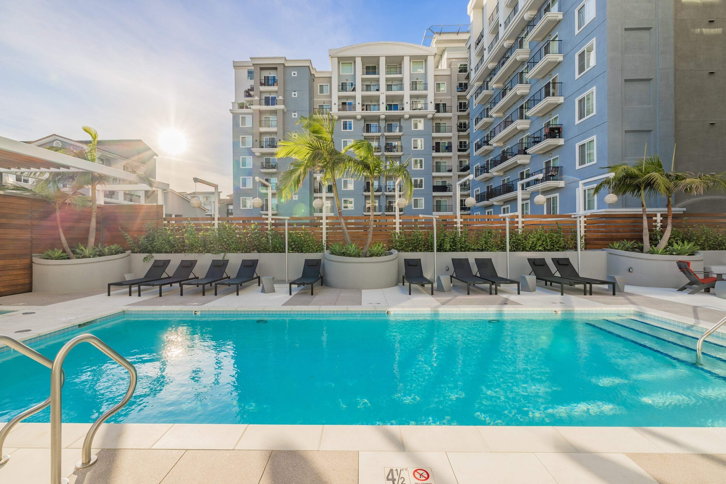 A swimming pool with lounge chairs and a view of a multi-story building.