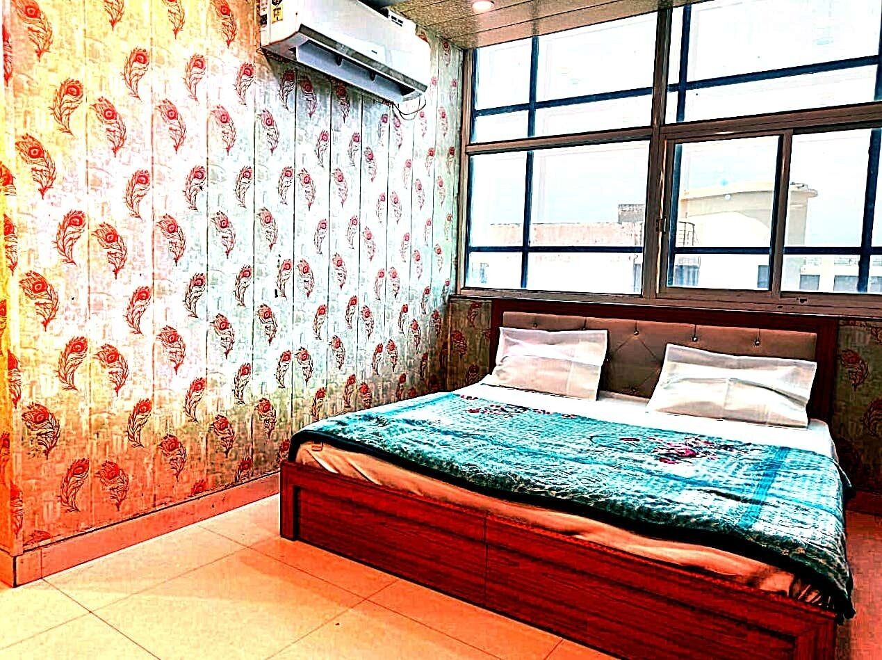 A bedroom with a bed, a window, and a wall with a floral pattern.