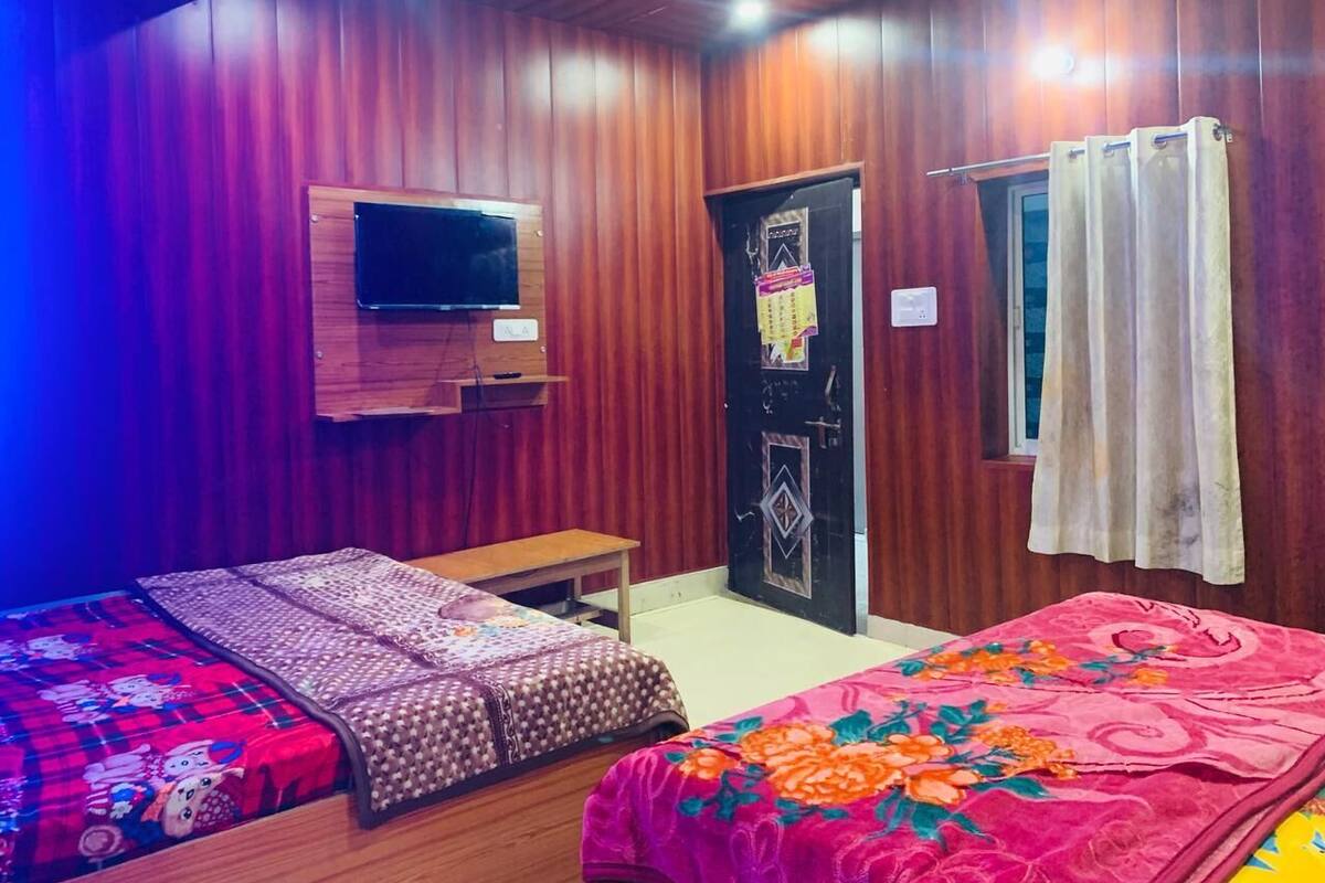 A room with two beds, a TV, a small table, and a door with a decorative panel.