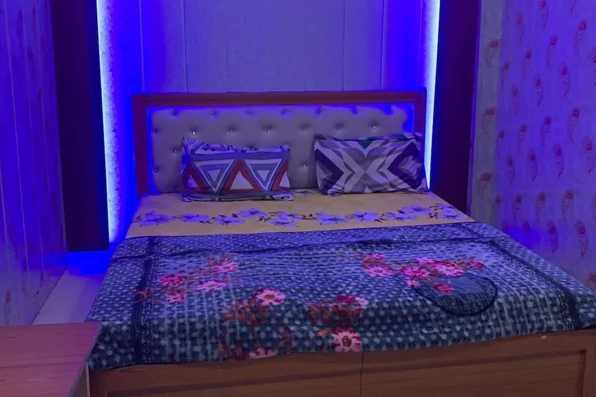 A bedroom with a tufted headboard, patterned bedding, and a wooden bed frame.