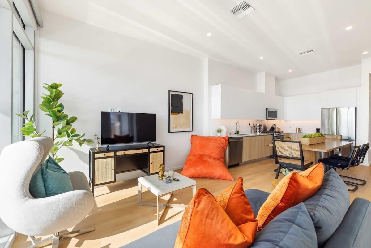 Una sala de estar moderna con un sofá, televisión, comedor y cocina.
