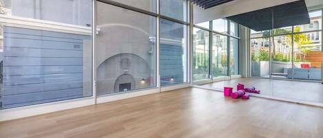 A spacious room with large windows, a fireplace, and wooden flooring.