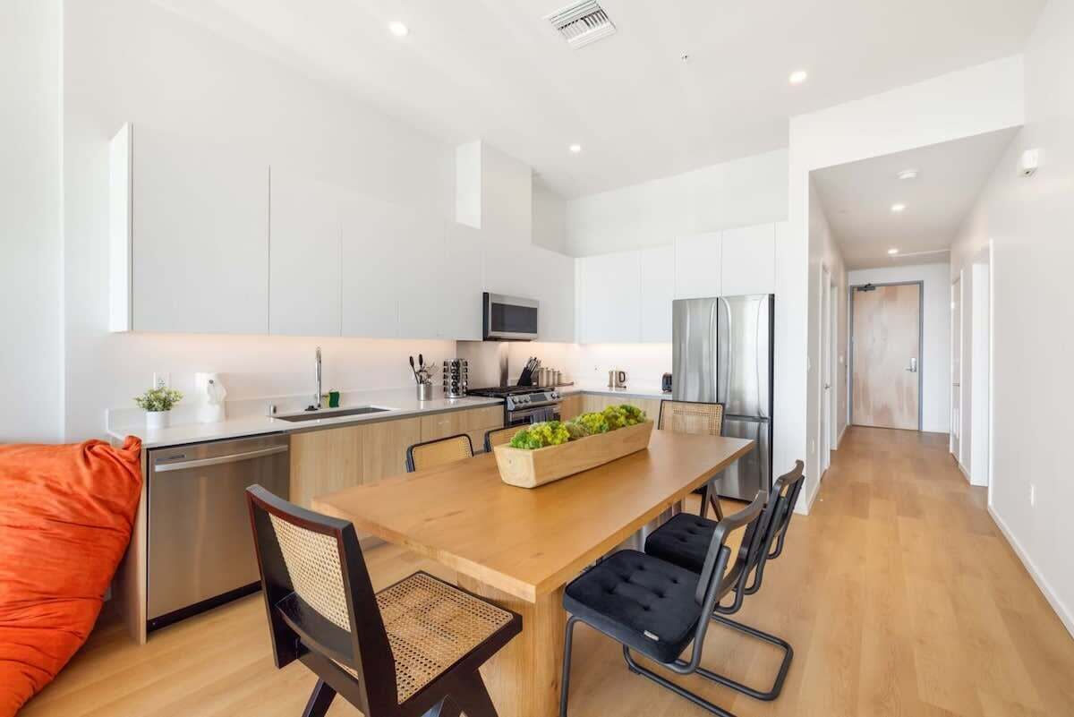 A modern kitchen with a wooden dining table, black chairs, and a built-in herb garden.