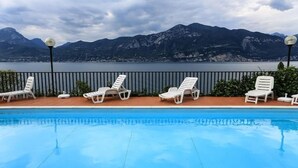 Una piscina con sillas de descanso blancas y vistas a montañas.