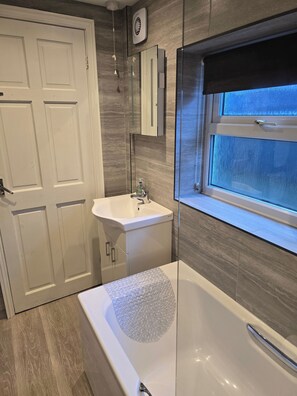 A modern bathroom with a bathtub, a sink, and a window. - Eden Rose Cottage in Morecambe hot tub (Morecambe)
