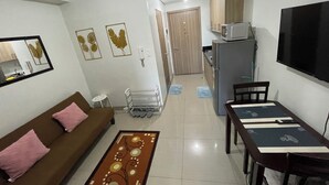 Un espacio habitable compacto con kitchenette, comedor y sofá con cojines.