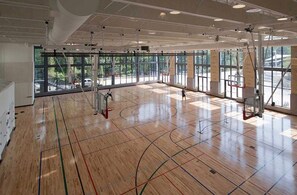 A spacious indoor basketball court with high ceilings, large windows, and visible structural beams. - Modern Luxury | DC | Free Parking (Arlington)