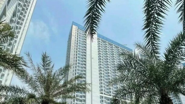 A high-rise building with a modern design, surrounded by palm trees and a glass structure. - Cozy Clean Nice Puri Mansion Apartment (Jakarta)