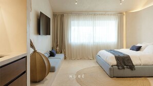 A modern bedroom with a bed, a TV, a large window with curtains, and a round rug. - Aesthetic Design Suite Aire with Pool (Cancún)