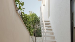 A narrow, white-walled corridor with a white staircase leading to an upper level. - Aesthetic Design Suite Aire with Pool (Cancún)