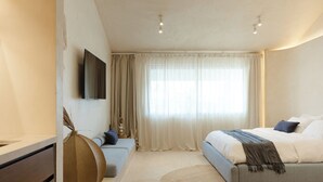 A modern bedroom with a bed, a TV, a large window with curtains, and a round rug. - Aesthetic Design Suite Aire with Pool (Cancún)