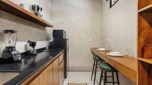 A compact kitchen with a countertop, a blender, a coffee maker, and a dining area with stools. - #NEW*Down Town Loft pool in the heart of Cancun (Cancún)