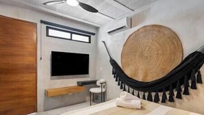 A modern bedroom with a large bed, a television, a wooden door, and a hammock. - #NEW*Down Town Loft pool in the heart of Cancun (Cancún)