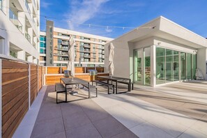 A modern outdoor patio with a wooden fence, a barbecue grill, and a glass-enclosed dining area. - @ Marbella Lane - Panoramic Delight Dream Escape! (Long Beach)