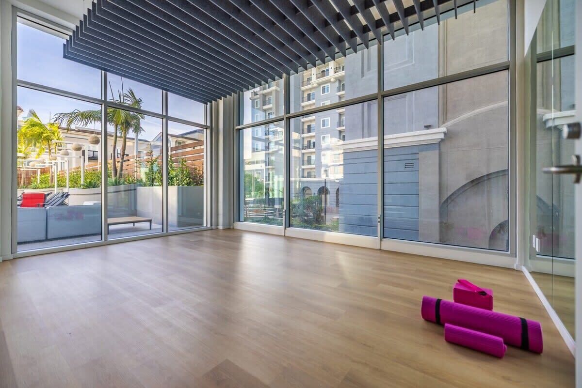 A spacious room with large windows, a wooden floor, and a ceiling with a slatted design.
