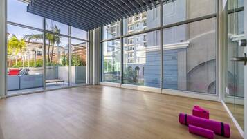 A spacious room with large windows, a wooden floor, and a ceiling with a slatted design.