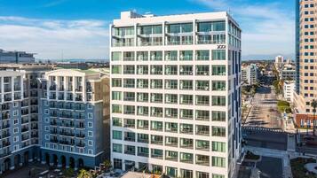 A modern multi-story hotel with a glass facade, multiple balconies, and a rooftop pool area.