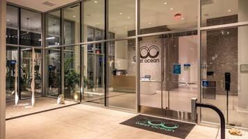 L'ingresso moderno di un hotel con porte in vetro, una reception e un chiosco informazioni digitale.