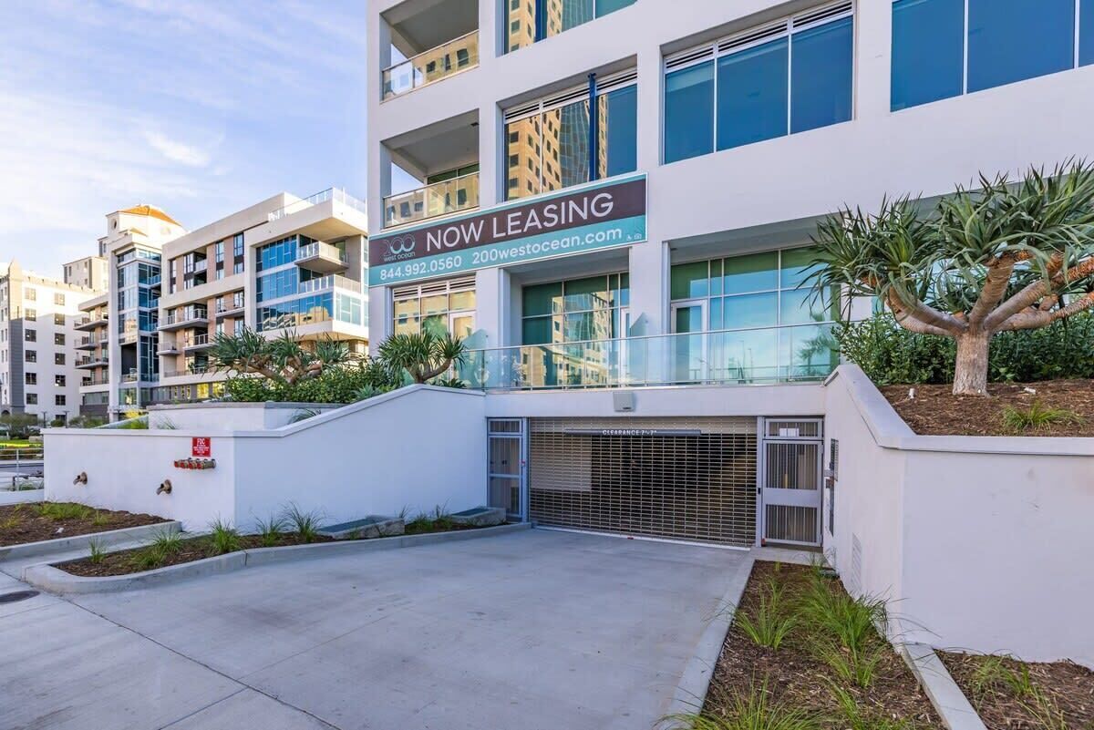 A modern multi-story building with a "NOW LEASING" sign, indicating available rental spaces.