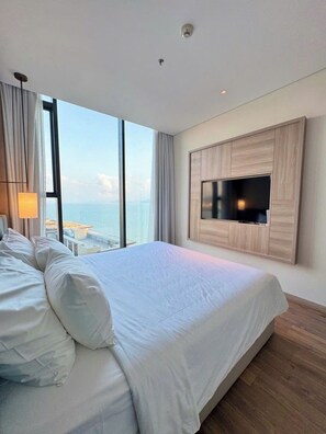 A modern hotel room with a large bed, a mounted TV, and a view of the sea. - Lotus Alacarte Ha Long Hotel (Bai Chay)
