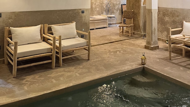 A spa area with wooden loungers, a small pool, and a view of a massage room. - Charming, recently renovated riad in the medina of Marrakech (Marrakech)