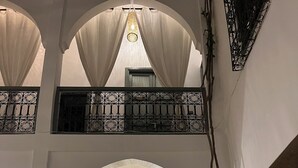 An arched entrance with a green door, a hanging light fixture, and a wicker chair. - Charming, recently renovated riad in the medina of Marrakech (Marrakech)