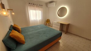 A bedroom with a bed, a desk, a chair, and a round mirror.