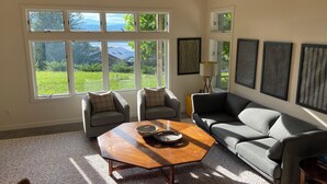 A living room with a large window, two armchairs, a sofa, and a coffee table. - An Apartment with a View: A peaceful getaway in Hudson, NY (Hudson)