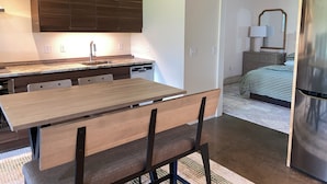 A modern kitchen with dark wooden cabinets, a built-in dishwasher, and a dining area with a wooden table and chairs. - An Apartment with a View: A peaceful getaway in Hudson, NY (Hudson)