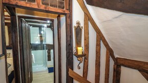 A narrow hallway with wooden beams and a glass door leading to a bathroom.