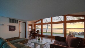 Un vaste salon doté de grandes fenêtres, un coin repas et une enseigne sur laquelle on peut lire : « BIENVENUE AU SURF SHACK ».