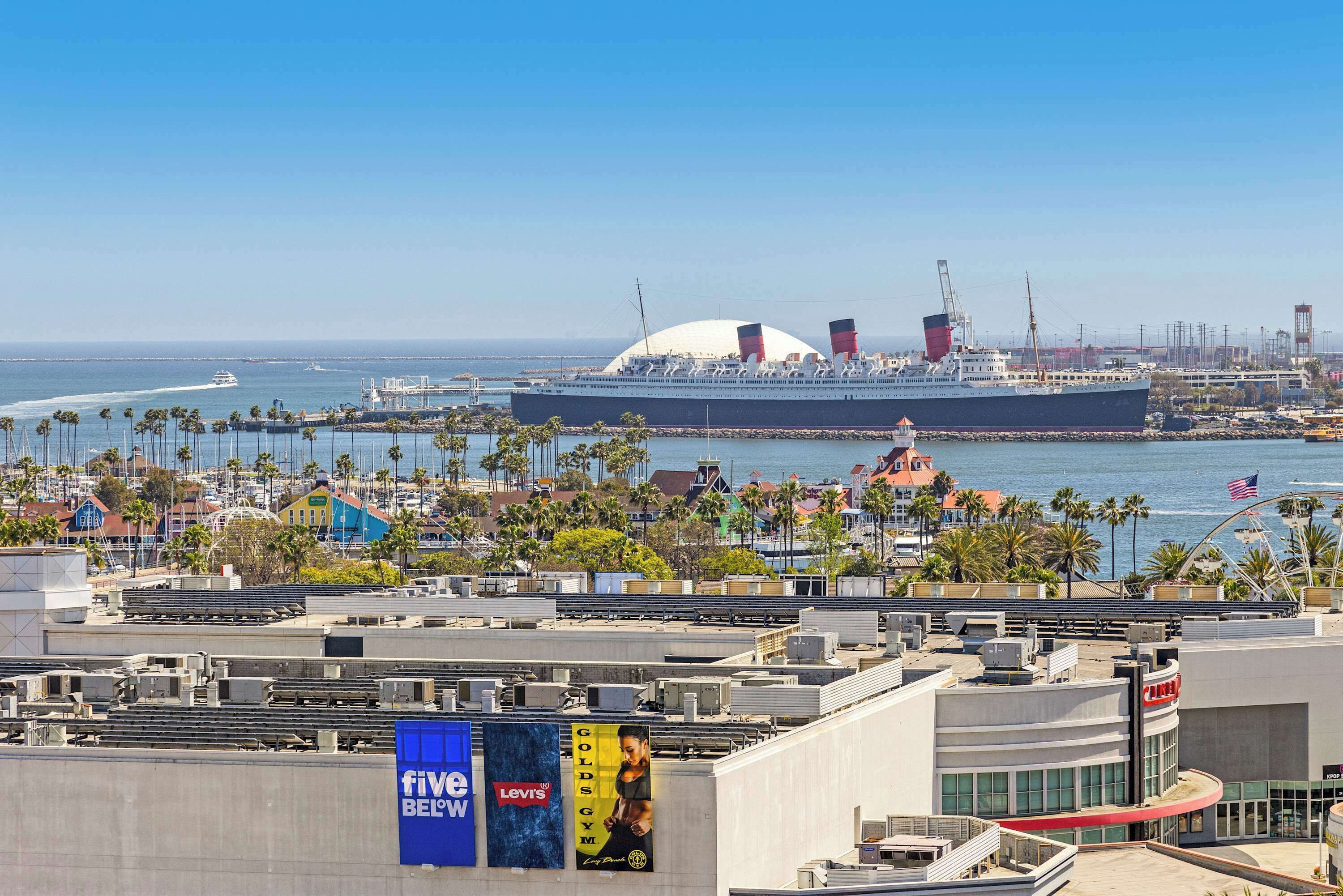 A large cruise ship docked at a port with a cityscape in the background.