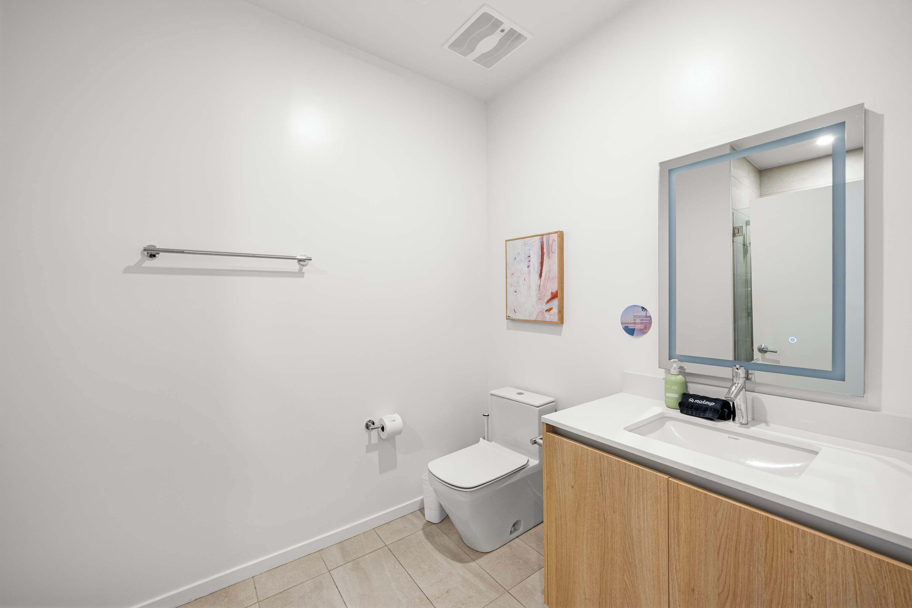 A modern bathroom with a toilet, sink, and mirror.