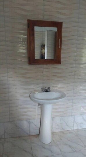 Bathroom features a pedestal sink and a wooden-framed mirror.