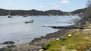 A coastal scene with boats on calm water, rocky shoreline, and hills in the background. - Ardtornish Apartment (Tayvallich)