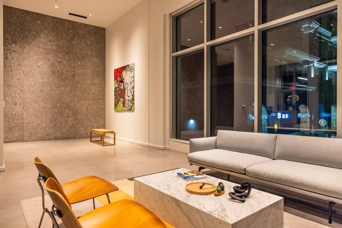 A modern living room with a marble coffee table, a grey sofa, and a wooden chair.