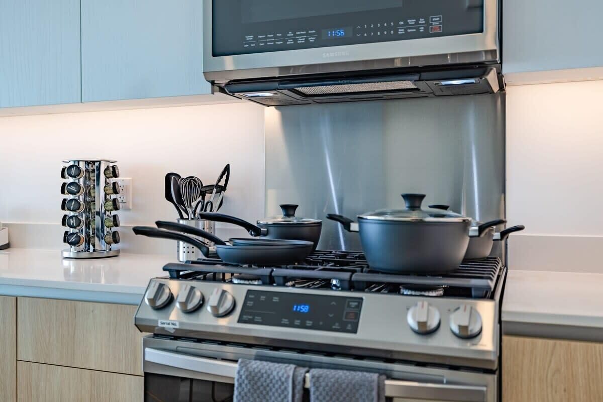 A modern kitchen with stainless steel appliances, including a stove and microwave, and a set of kitchen utensils on the counter.