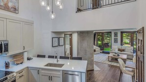 A modern kitchen with a central island, stainless steel appliances, and a dining area with a large window overlooking a garden.