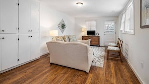 Una habitación con sofá, televisor, cómoda y una puerta.