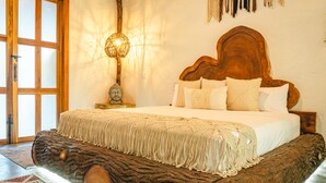 A bedroom with a wooden headboard, a Buddha statue, a woven blanket, and a lamp. - Anzalik Hotel Boutique (Anza)
