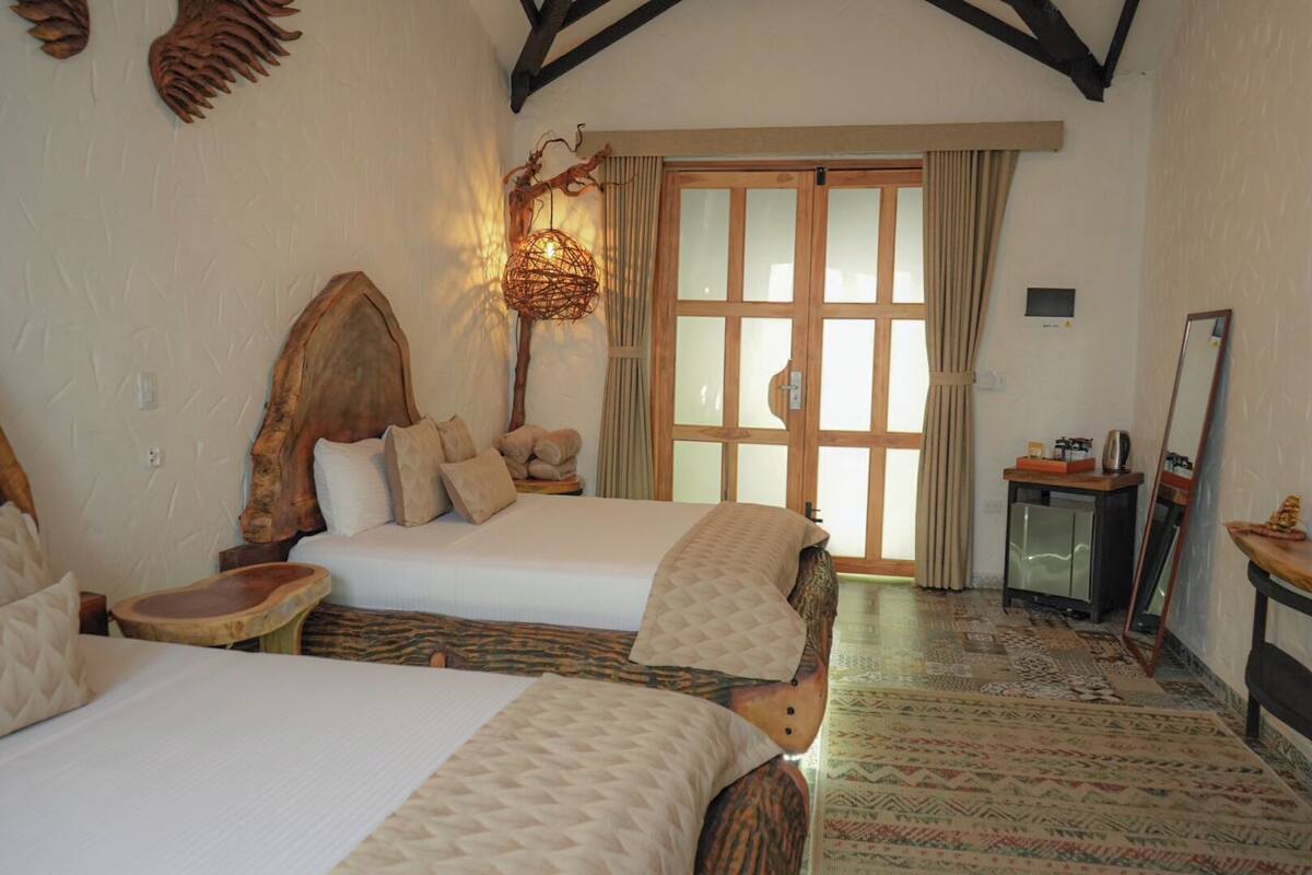 A hotel room with two beds, a wooden headboard, a small desk, and a mirror.